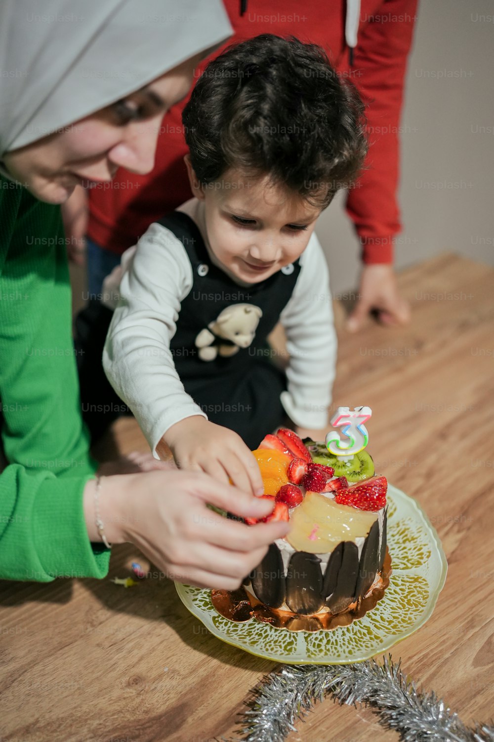 a woman and a child are decorating a cake
