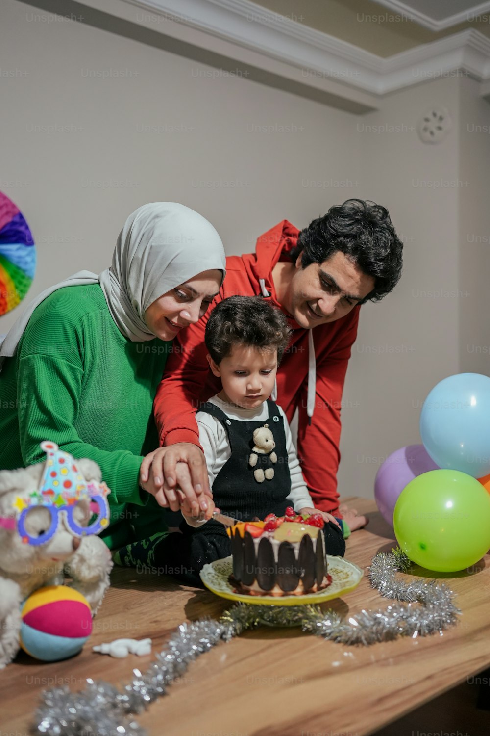 a man and a woman cutting a cake with a child