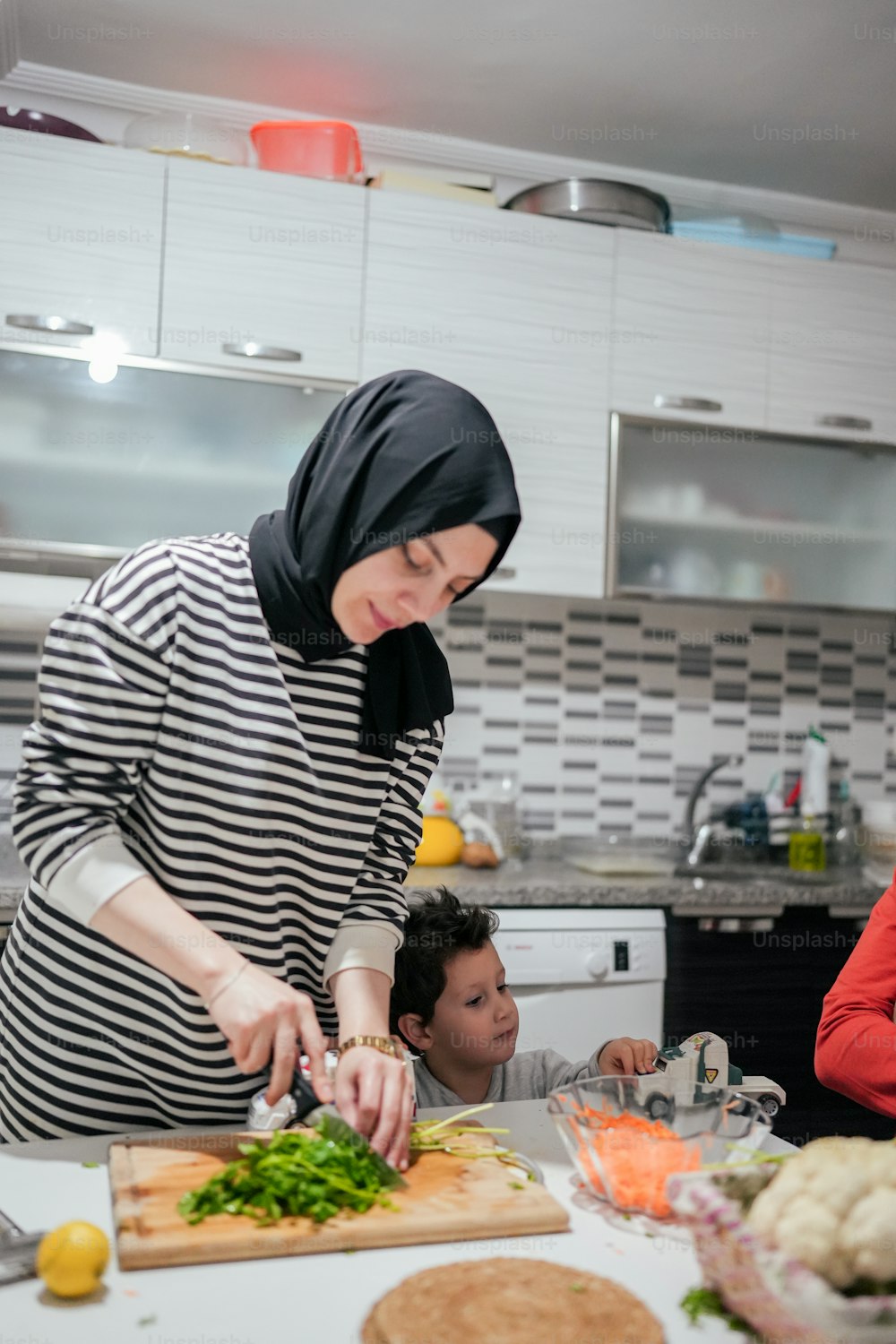 Une femme en hijab coupe des légumes sur une planche à découper