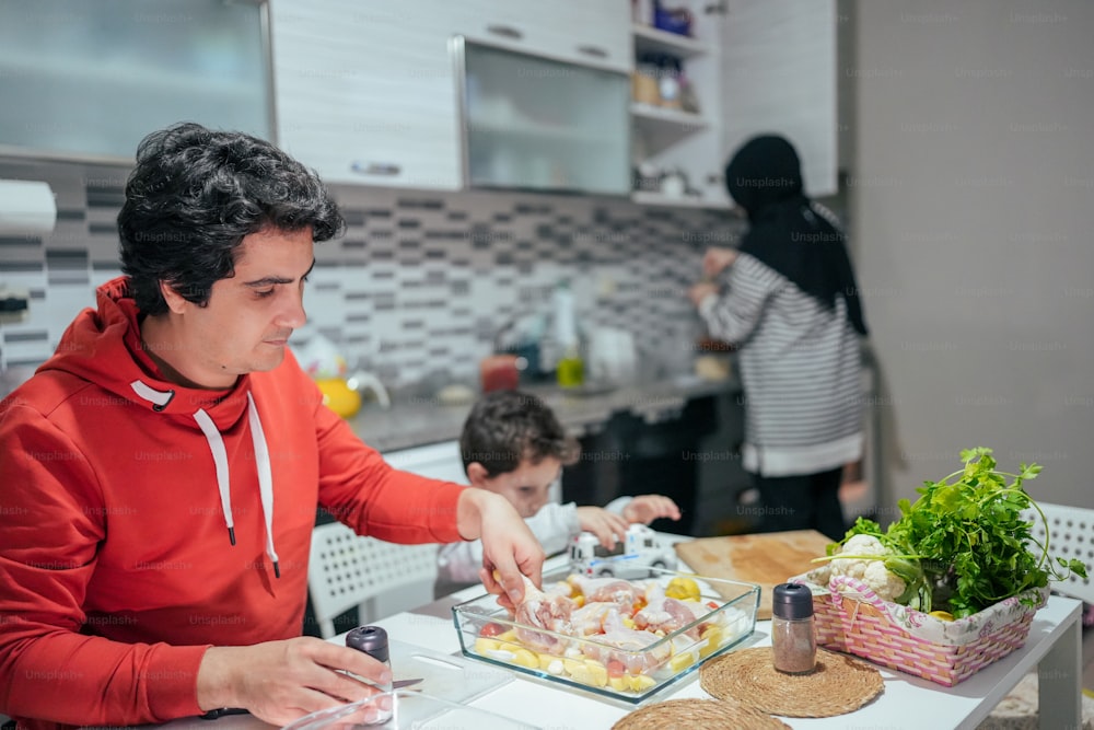 Un hombre con una sudadera con capucha roja preparando comida en una cocina