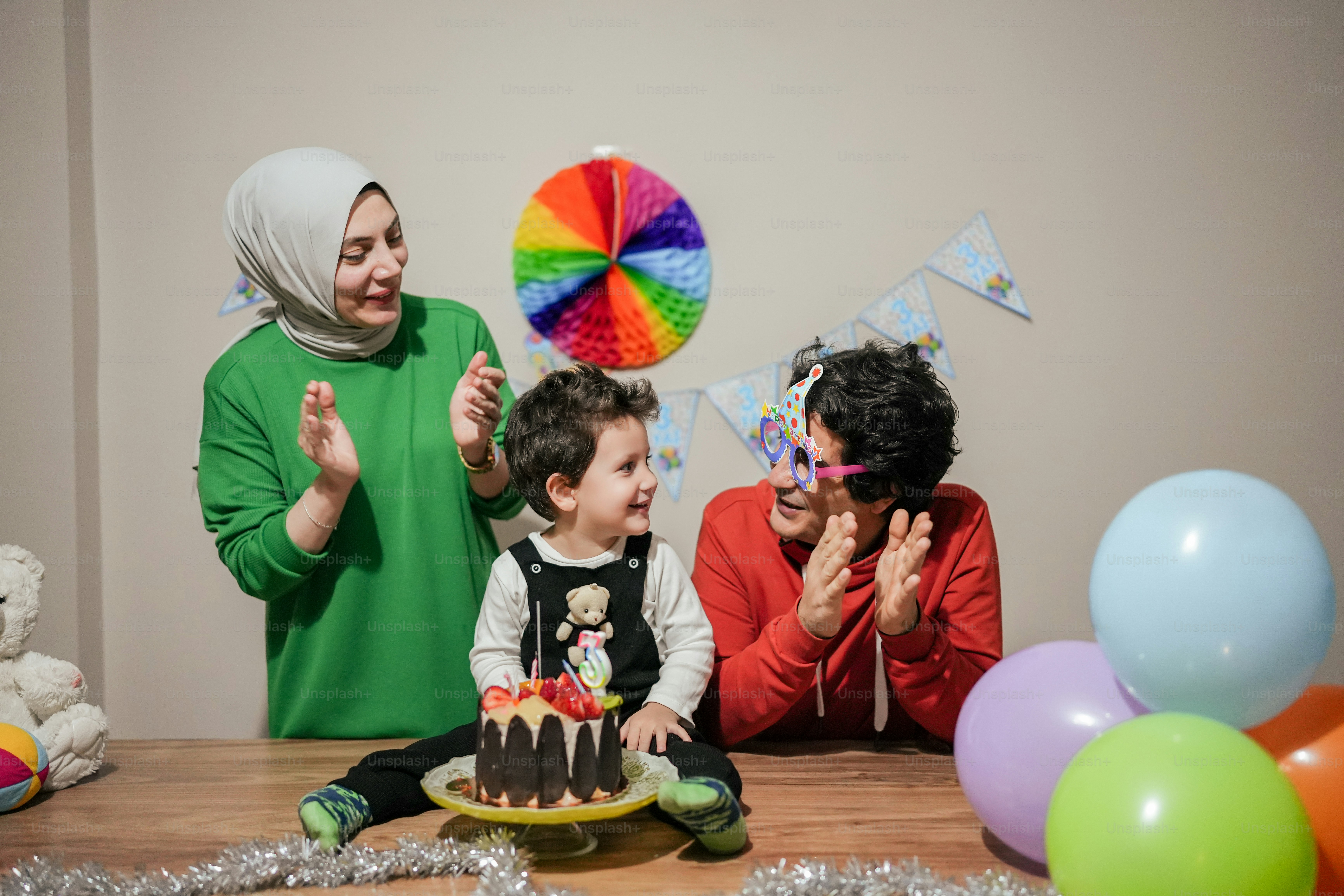 a woman and two children sitting in front of a cake