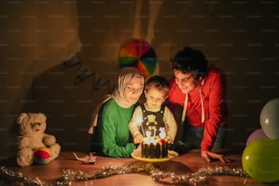 a woman and two children are looking at a birthday cake