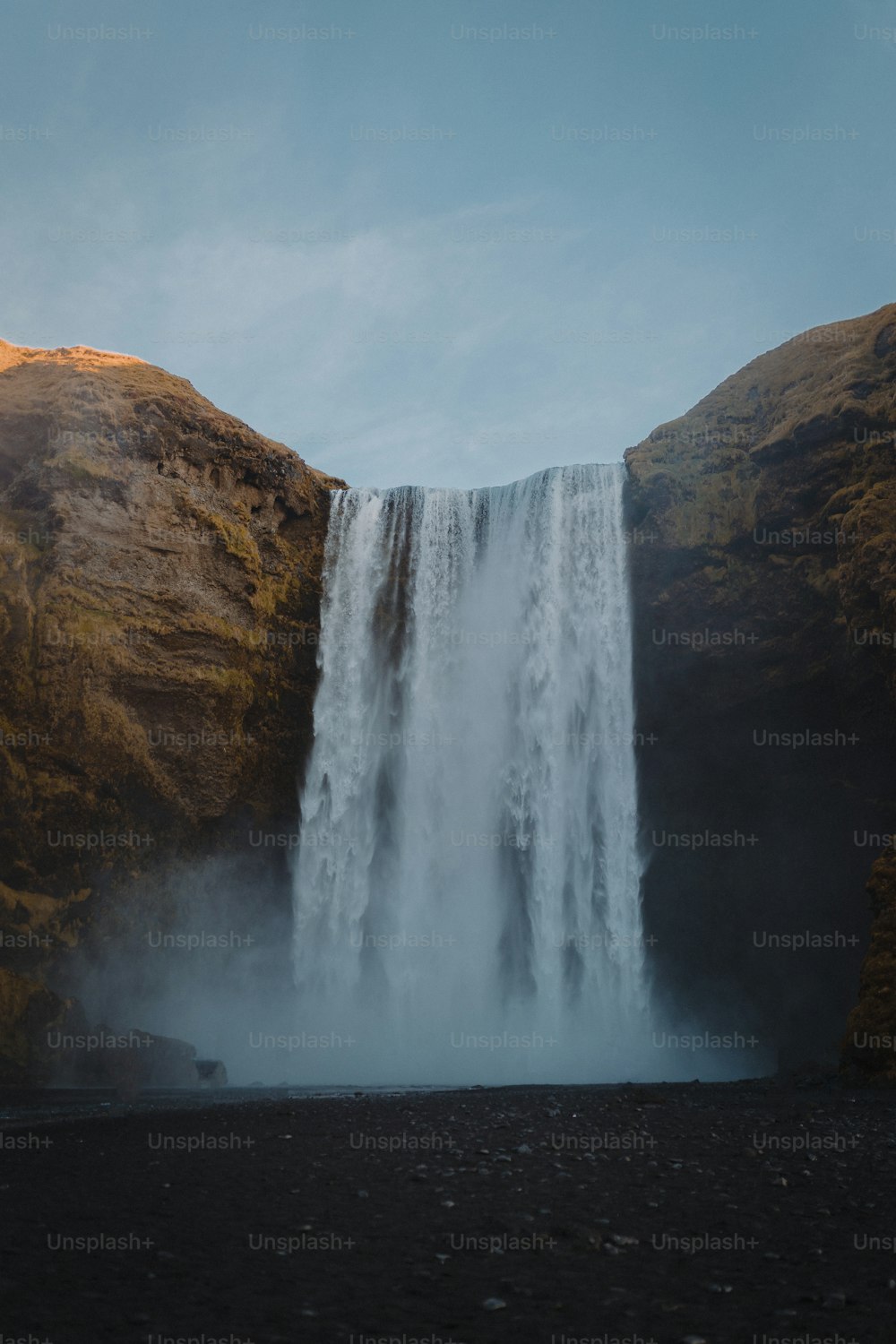 a large waterfall with water falling from it's sides