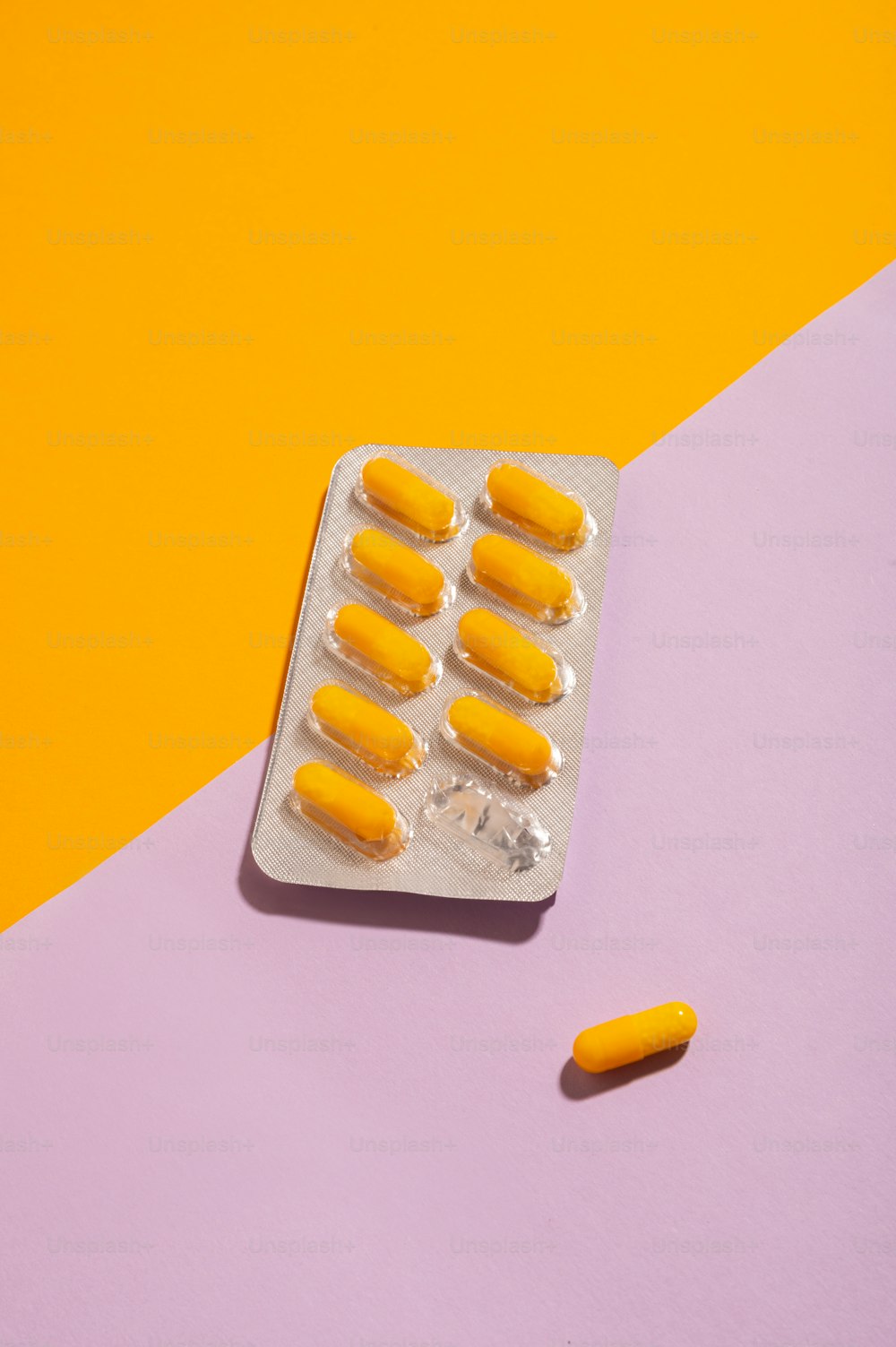 eine Vorrichtung gefüllt mit gelben Pillen auf rosa und gelbem Hintergrund