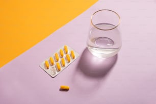 uma pílula e um copo de água em uma mesa