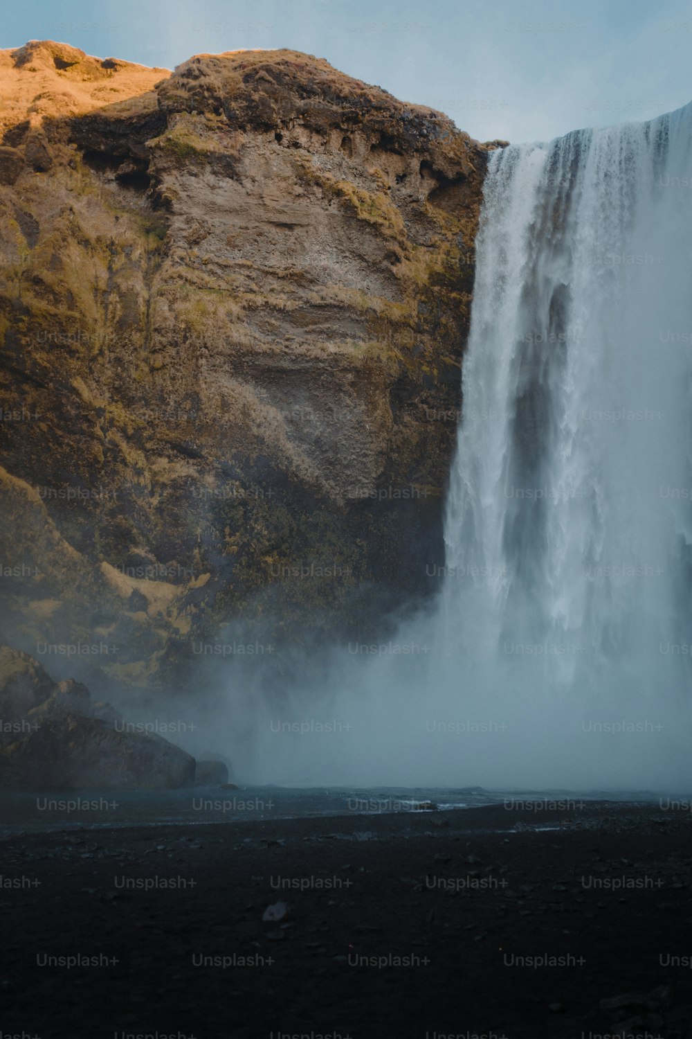 una grande cascata con un uomo in piedi di fronte ad essa