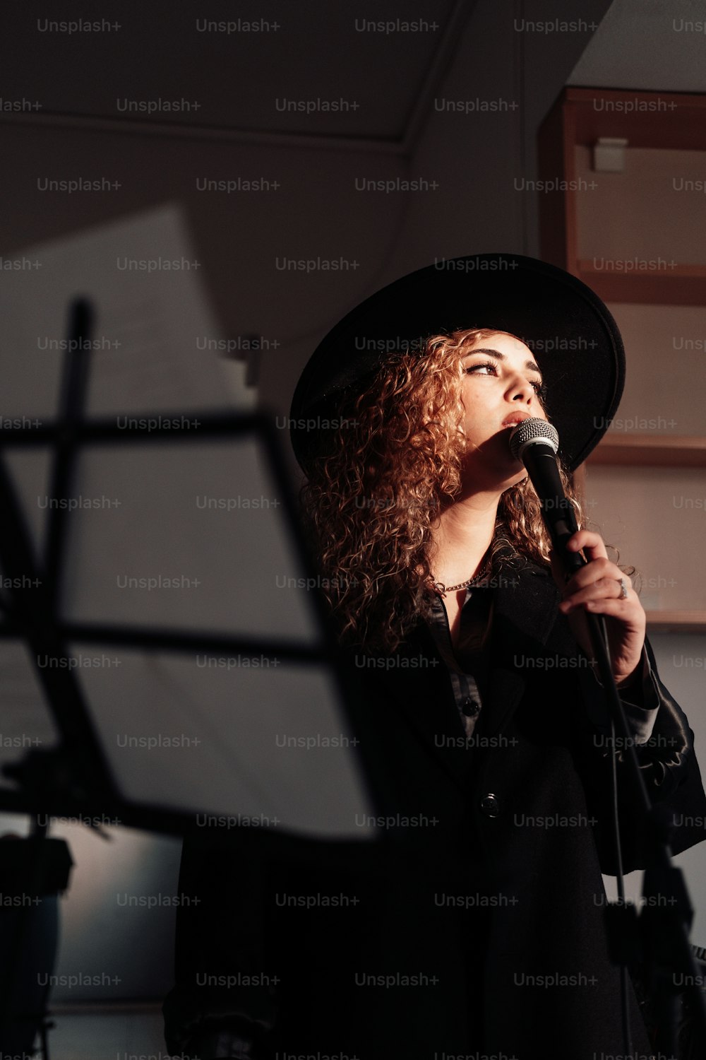 a woman in a black hat singing into a microphone