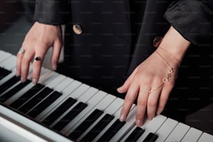 a person wearing a black suit and a gold bracelet playing a piano