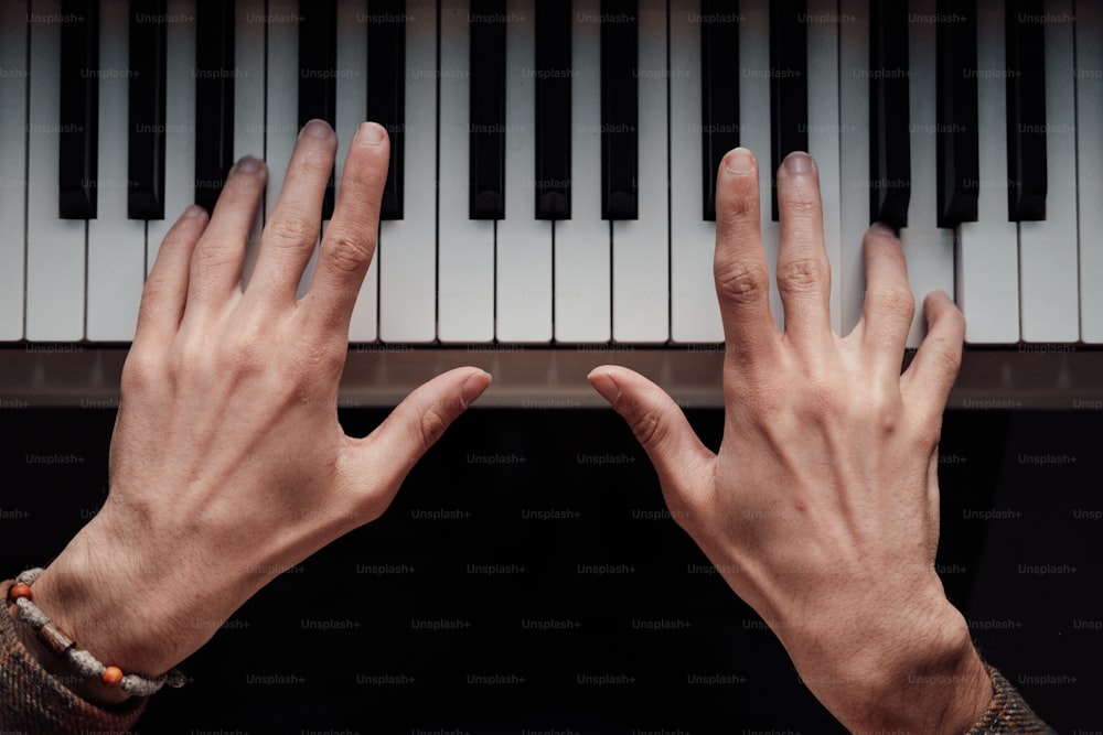 피아노 건반에 손을 뻗는 사람의 손