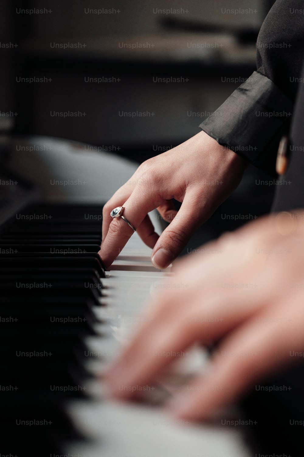 a person with a ring on their finger playing a piano