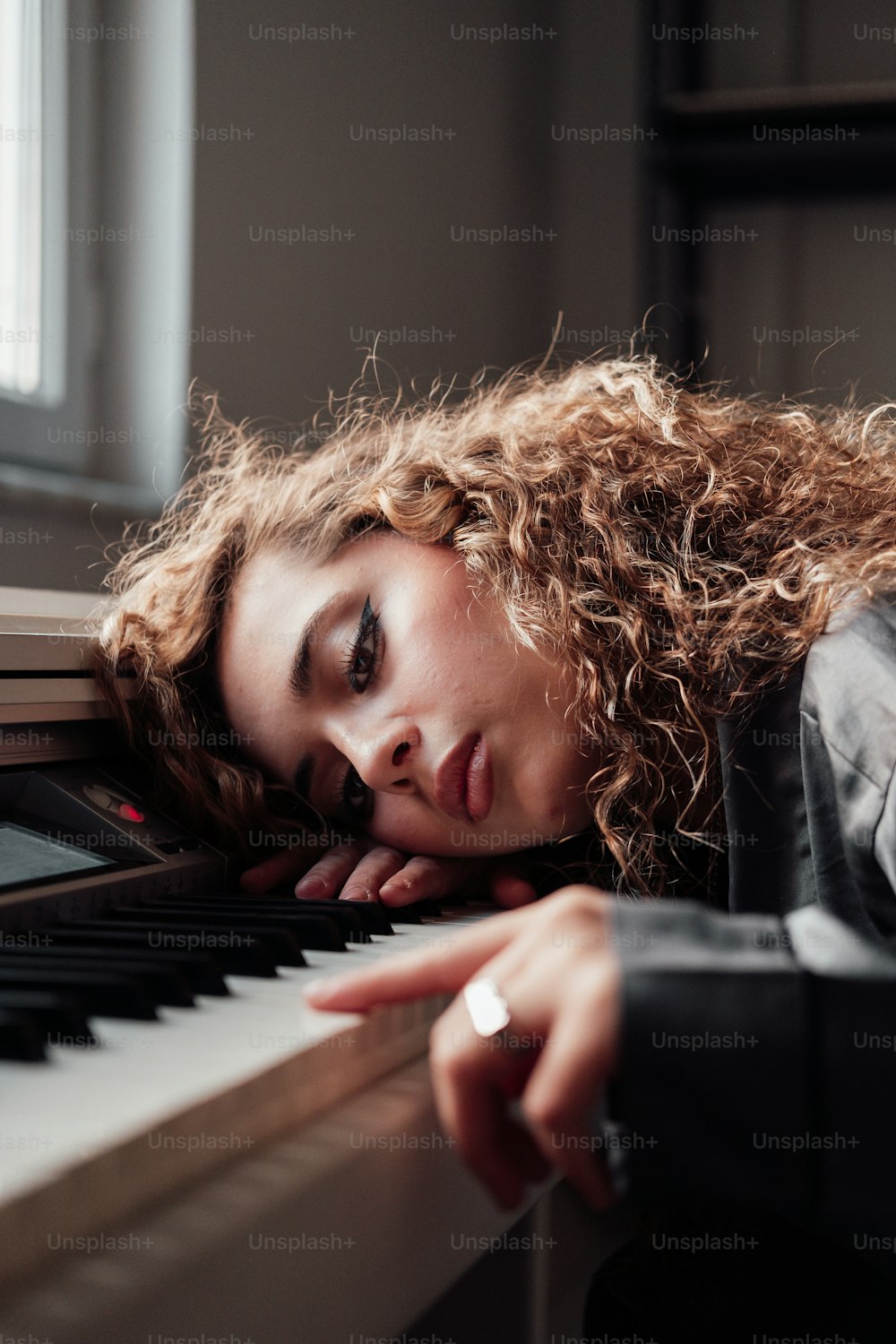 a woman leaning her head on a piano