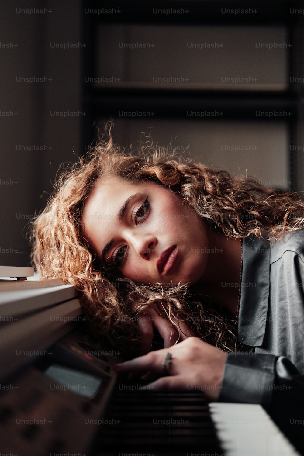 a woman leaning on a piano with her eyes closed