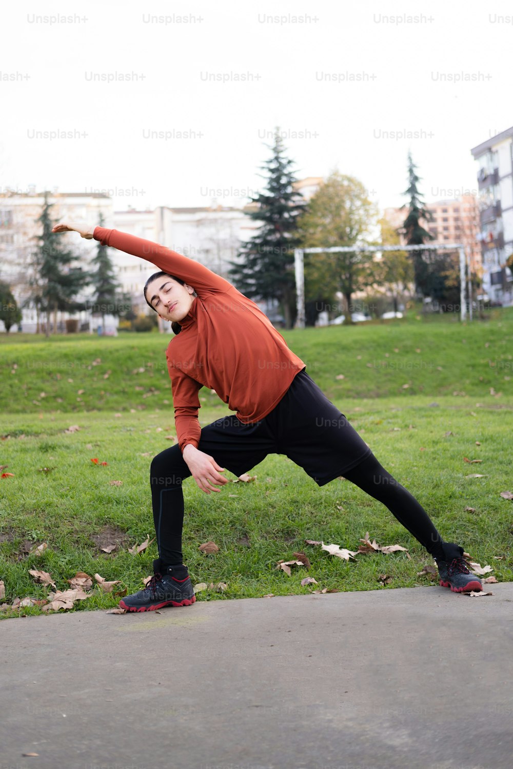 Un homme en chemise rouge fait une pose de yoga