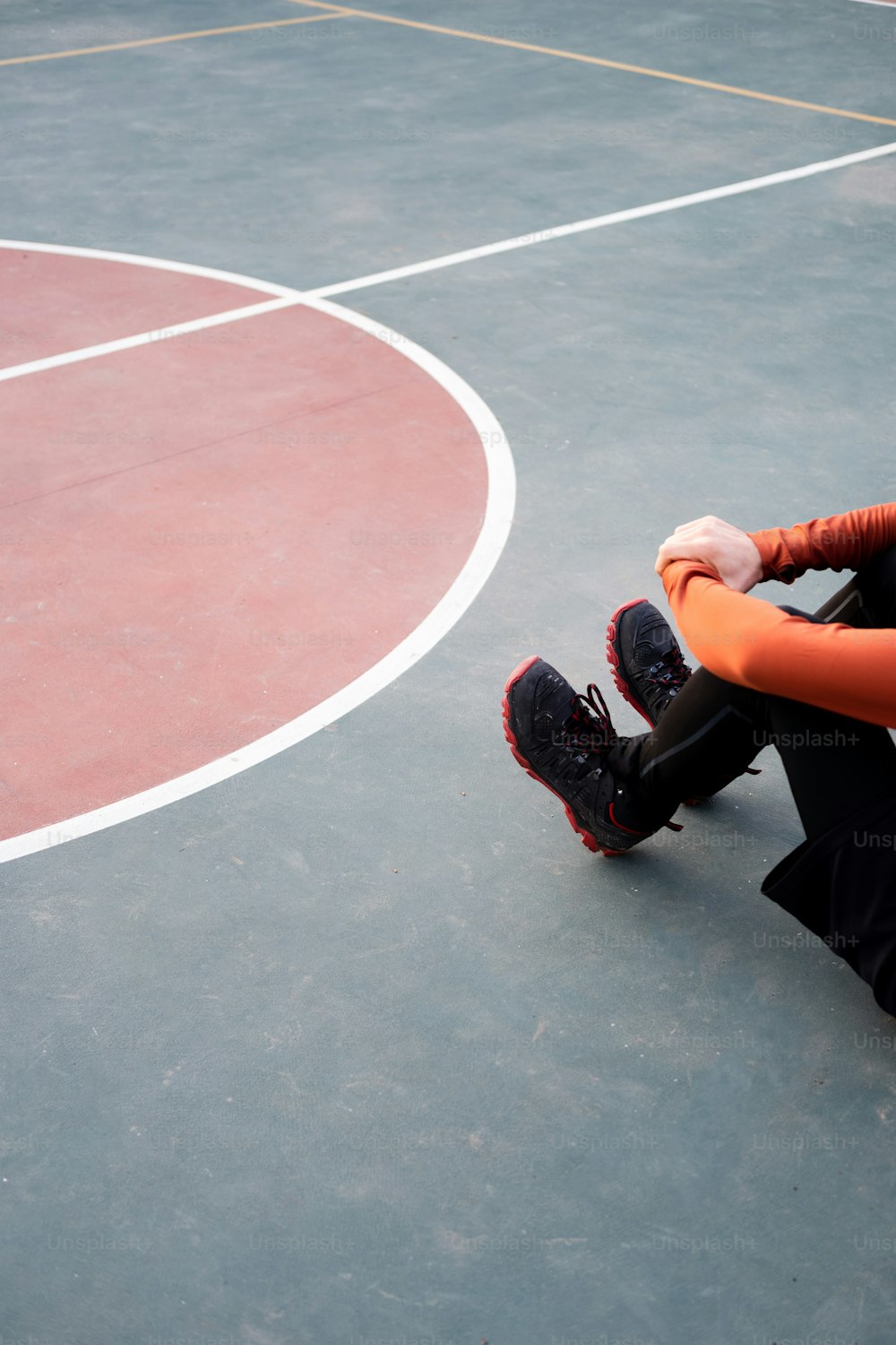 a man sitting on a basketball court with his feet on the ground