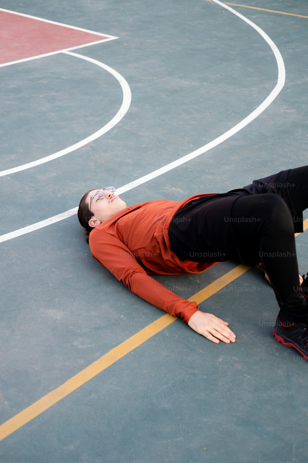 a person laying on the ground on a basketball court