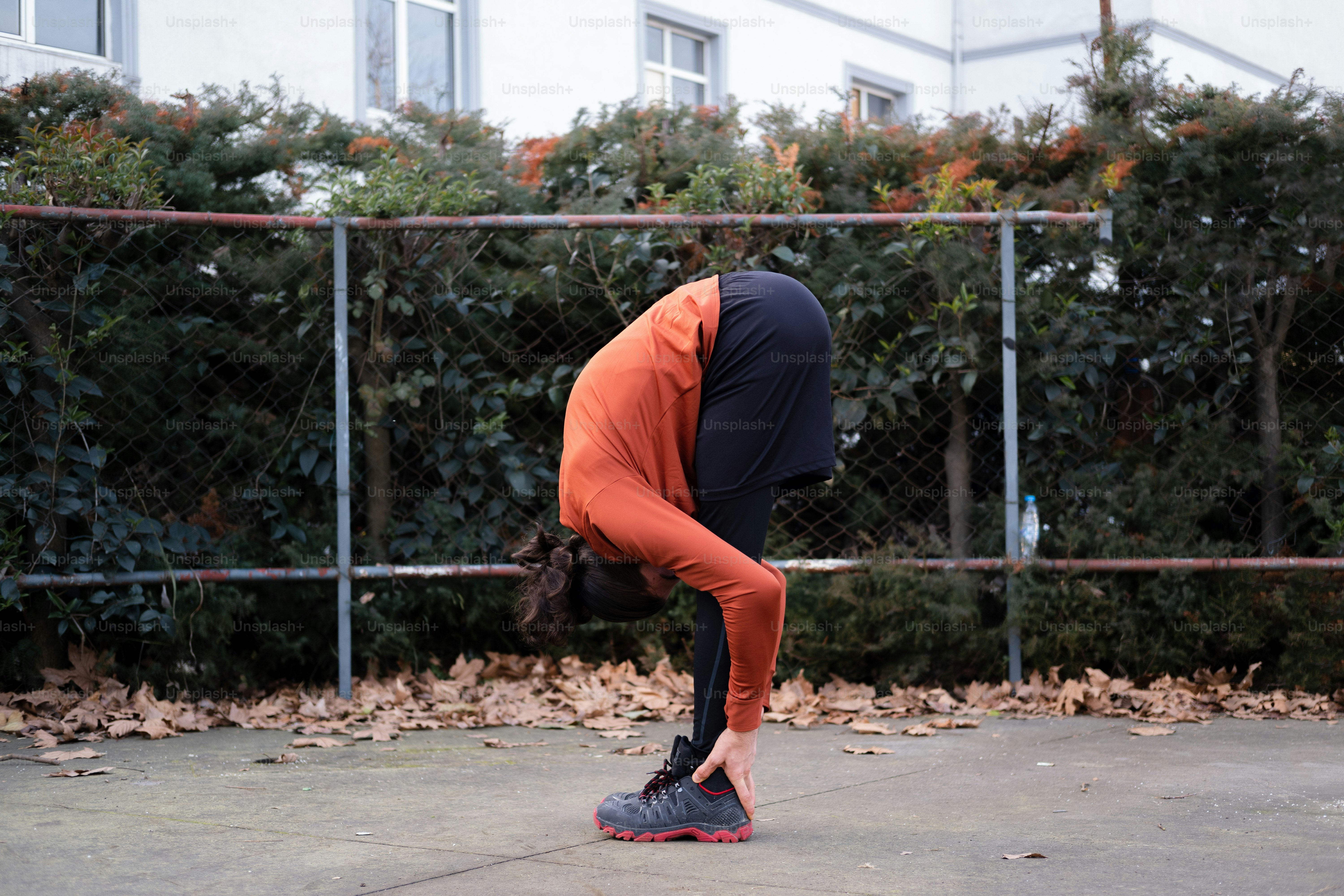 Eine Person in einem orangefarbenen Hemd macht einen Handstand auf einem Skateboard