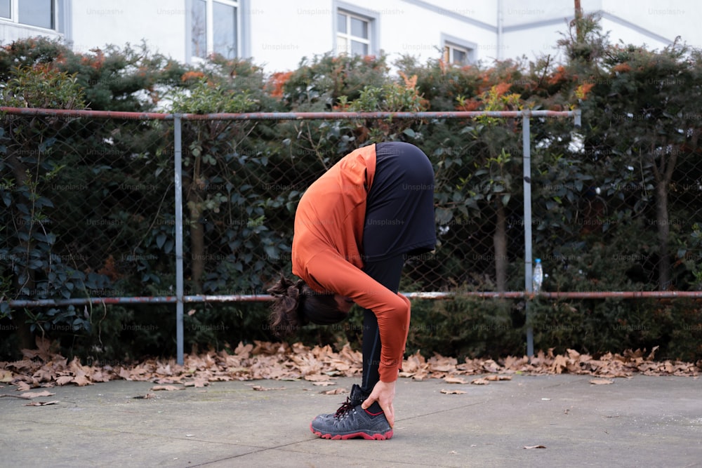 a person in an orange shirt doing a handstand on a skateboard