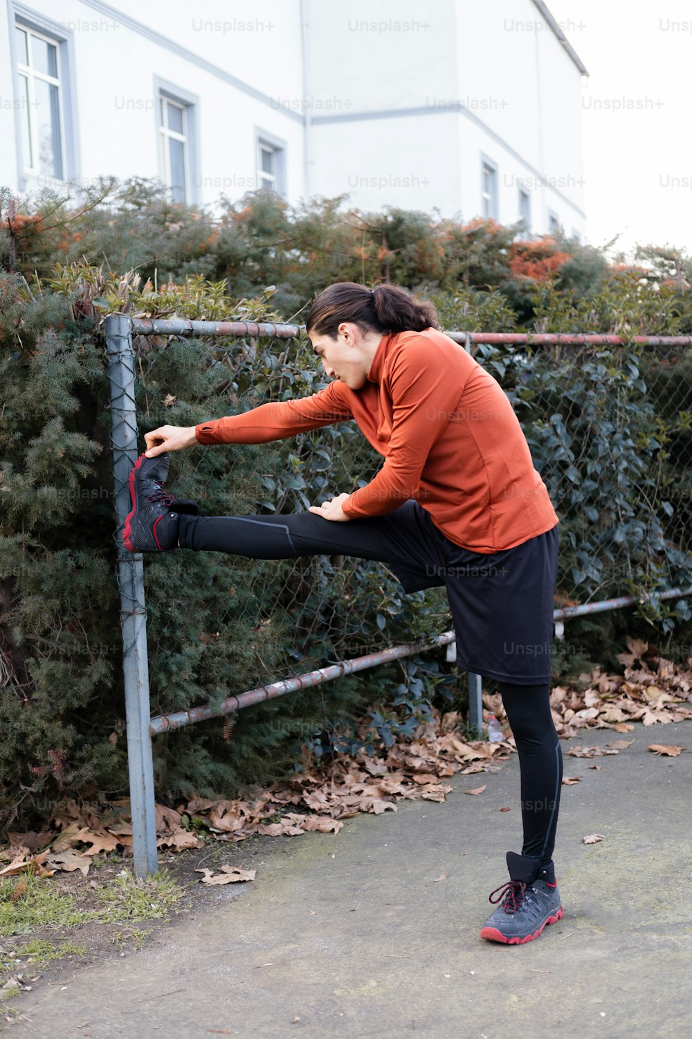 uma mulher esticando as pernas em uma cerca