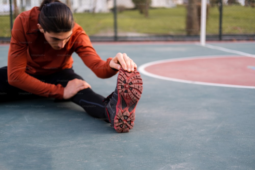 a woman sitting on a basketball court with her feet on the ground