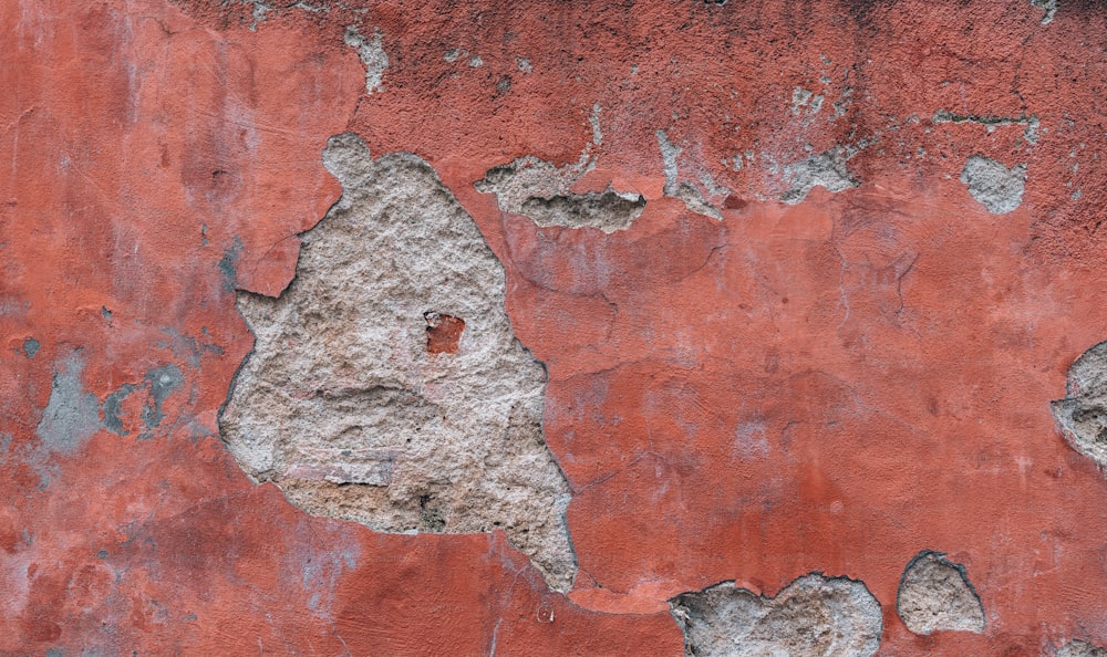 un mur rouge avec de la peinture écaillée dessus
