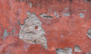 a red wall with peeling paint on it