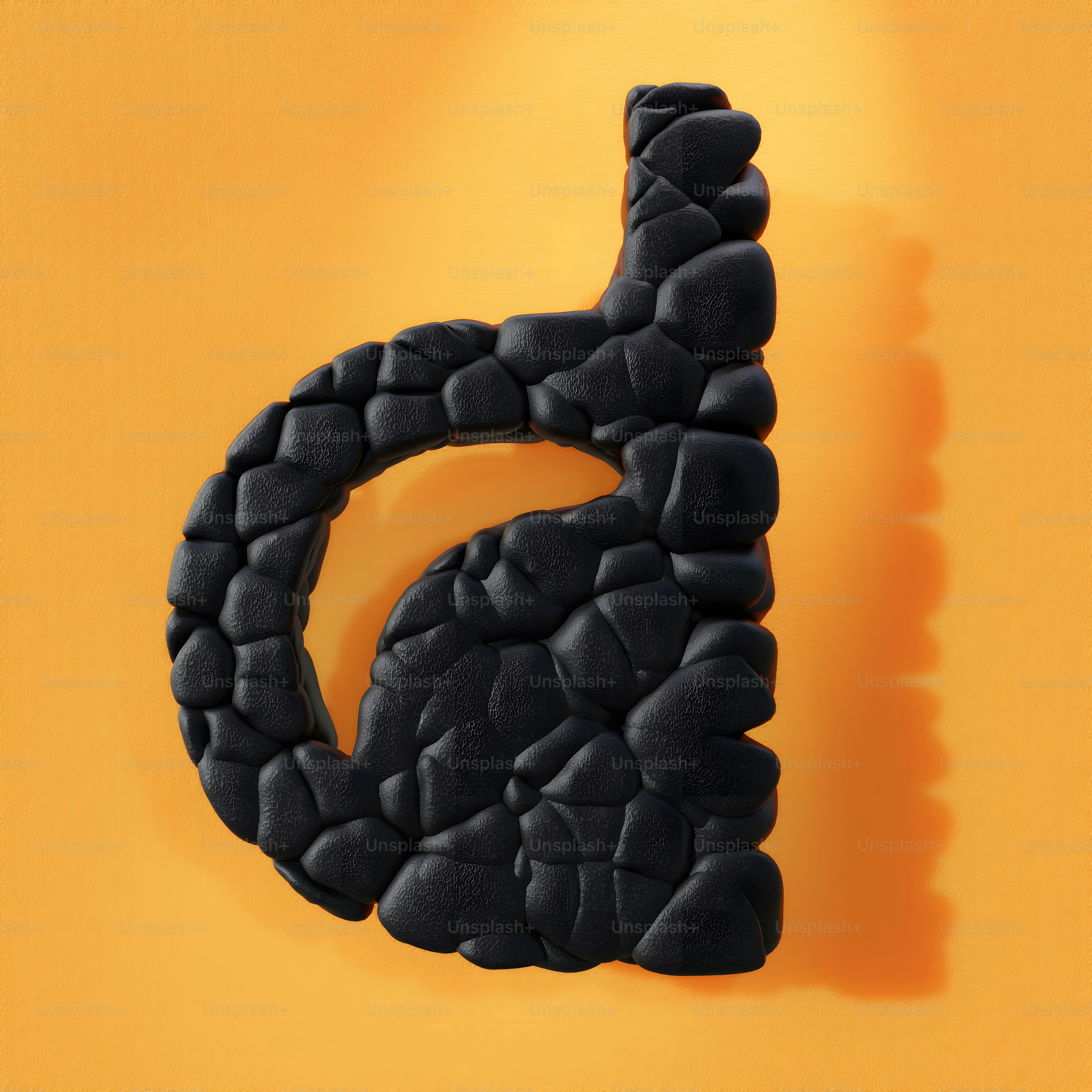 a black letter made out of rocks on a yellow background