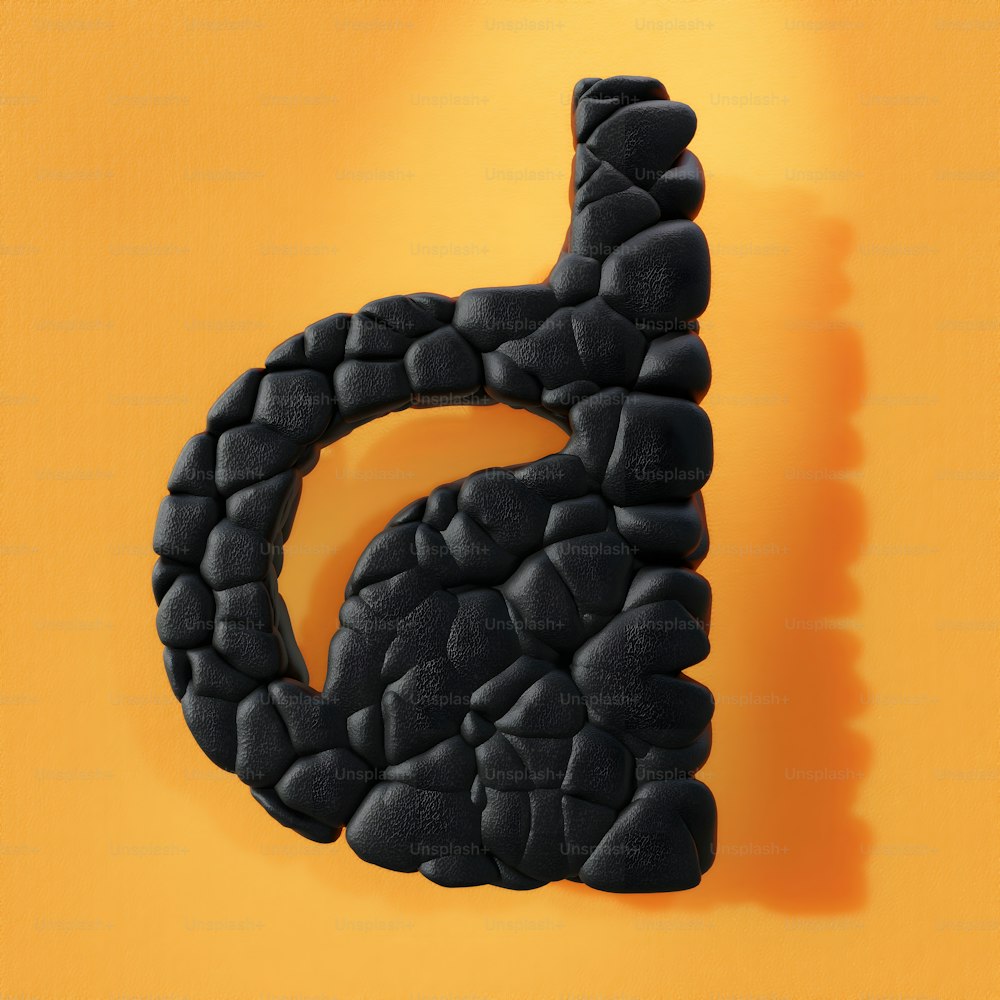 a black letter made out of rocks on a yellow background