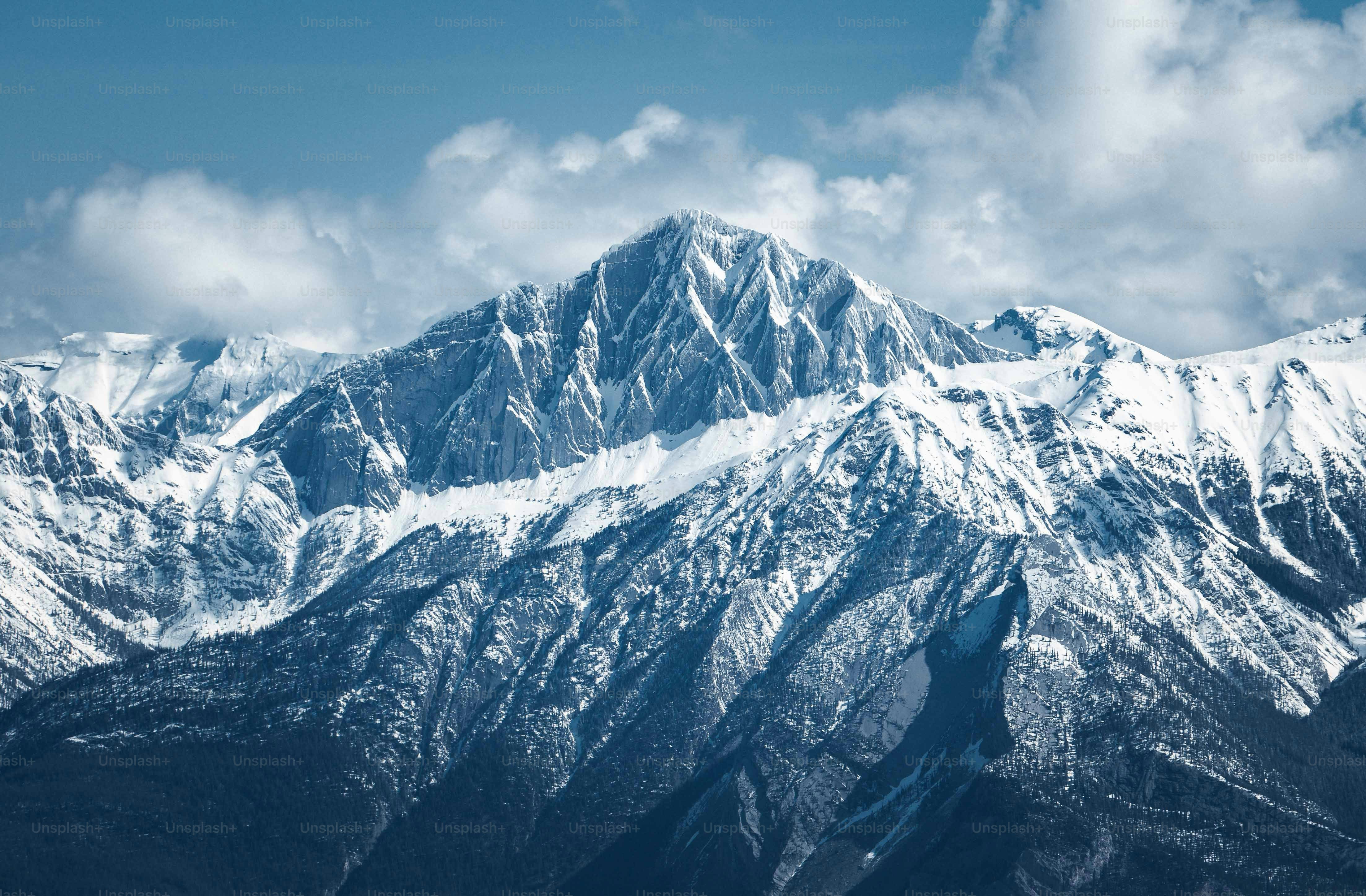 a mountain range covered in snow under a blue sky
