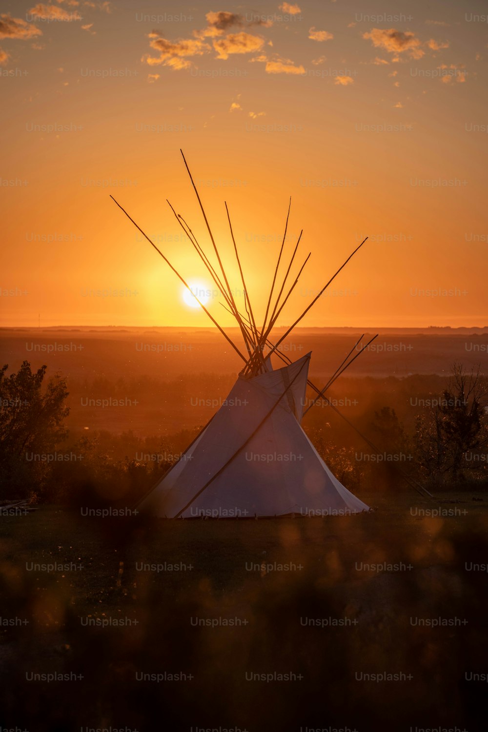 a teepee with the sun setting in the background