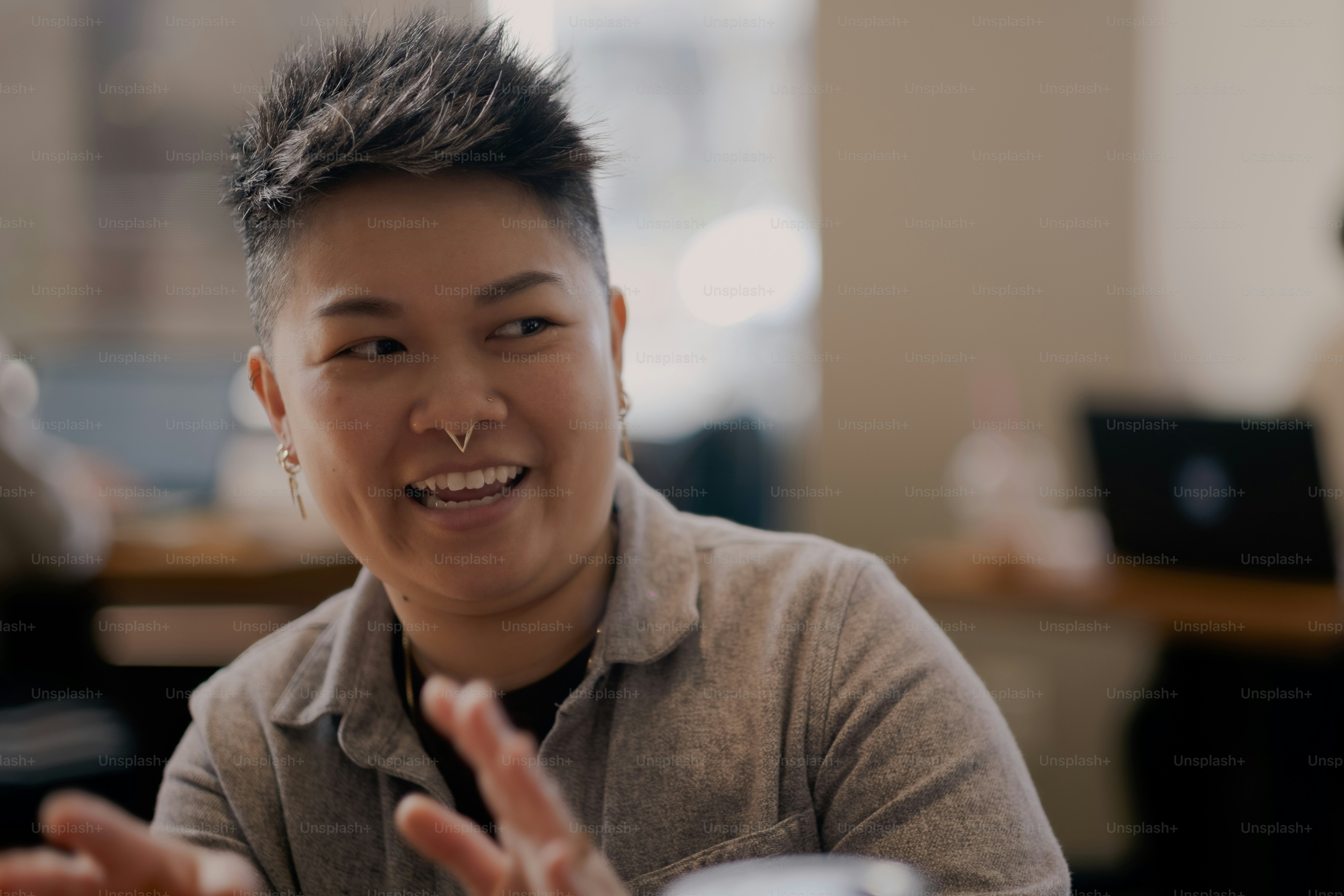 Eine Frau sitzt mit einem Lächeln im Gesicht an einem Tisch