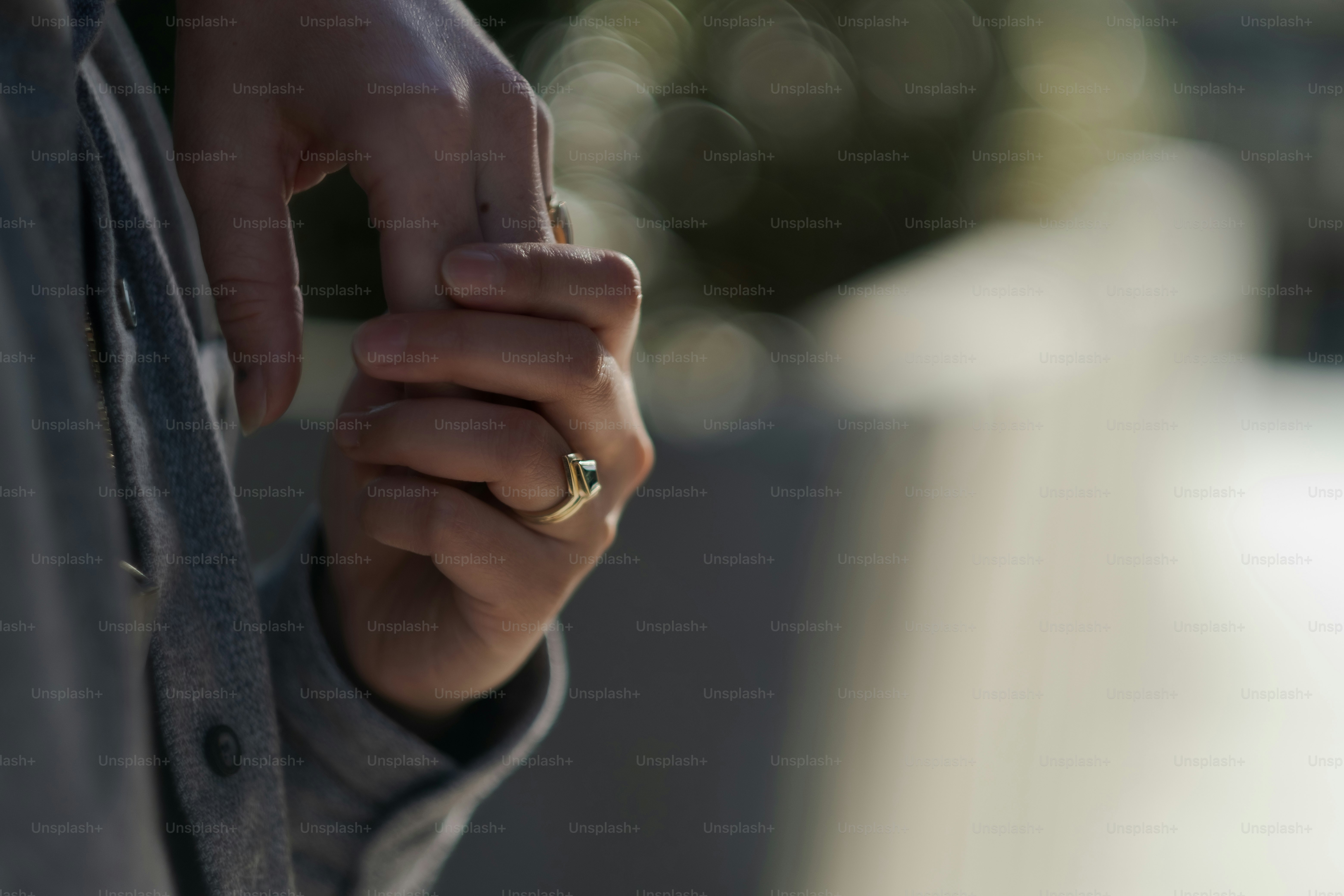 J. and M., a nonbinary queer couple, express their love by holding each other's hands and showing their engagement rings.