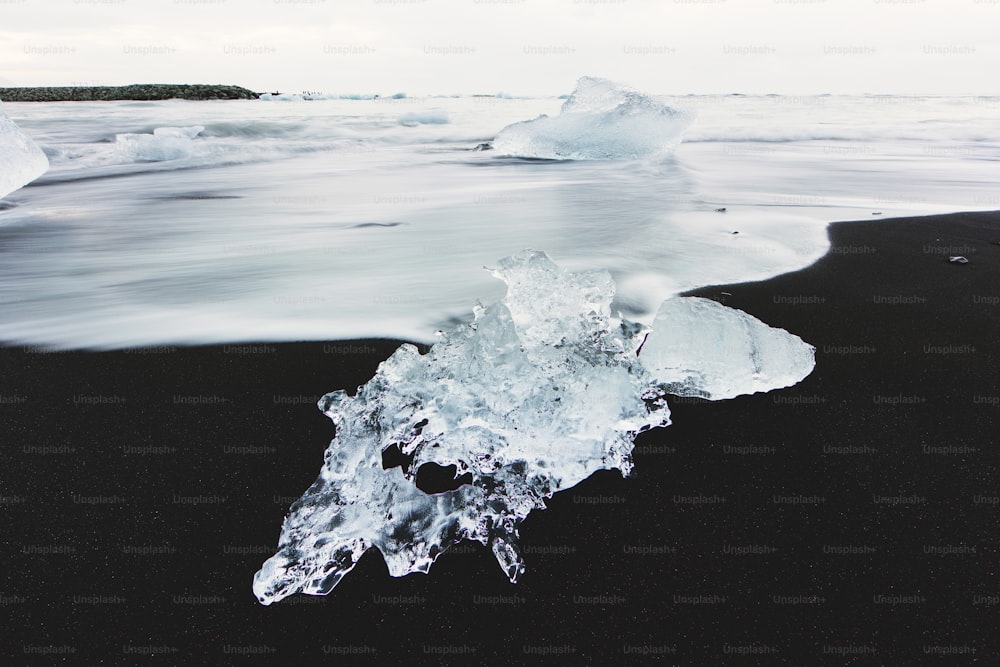 an iceberg floating on top of a black sand beach