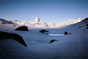 a snow covered mountain with a small pool of water