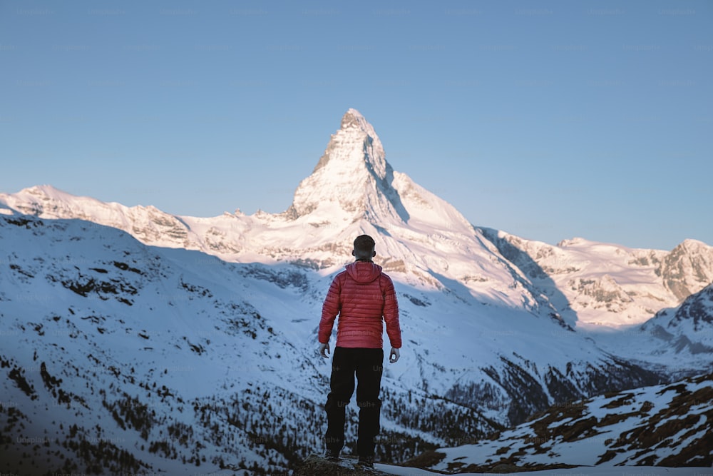 um homem de pé no topo de uma montanha coberta de neve