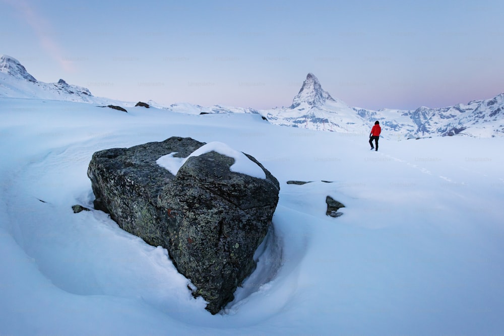 Un uomo in piedi sulla cima di una montagna coperta di neve