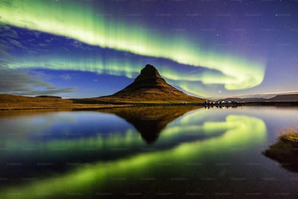 the aurora bore is reflected in the still water of a lake