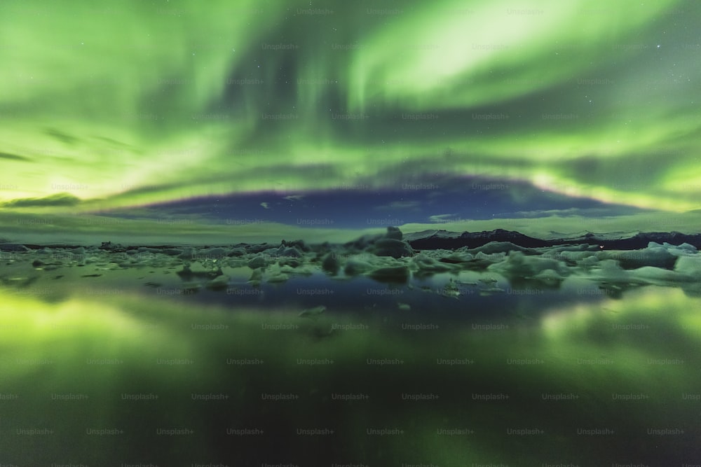 a green and purple sky with icebergs in the foreground