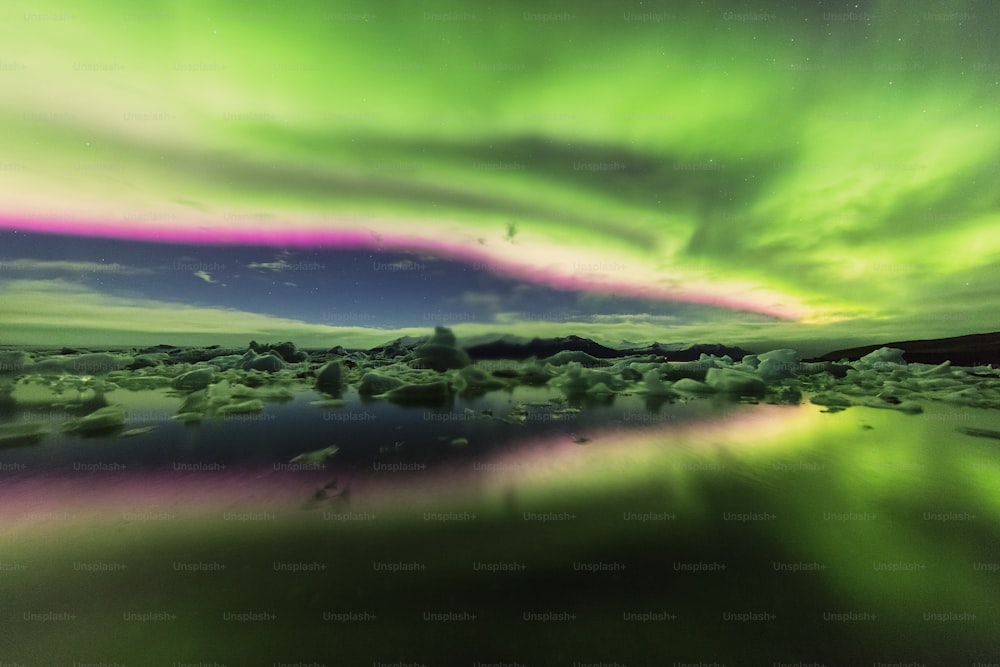 a green and purple aurora bore over a body of water