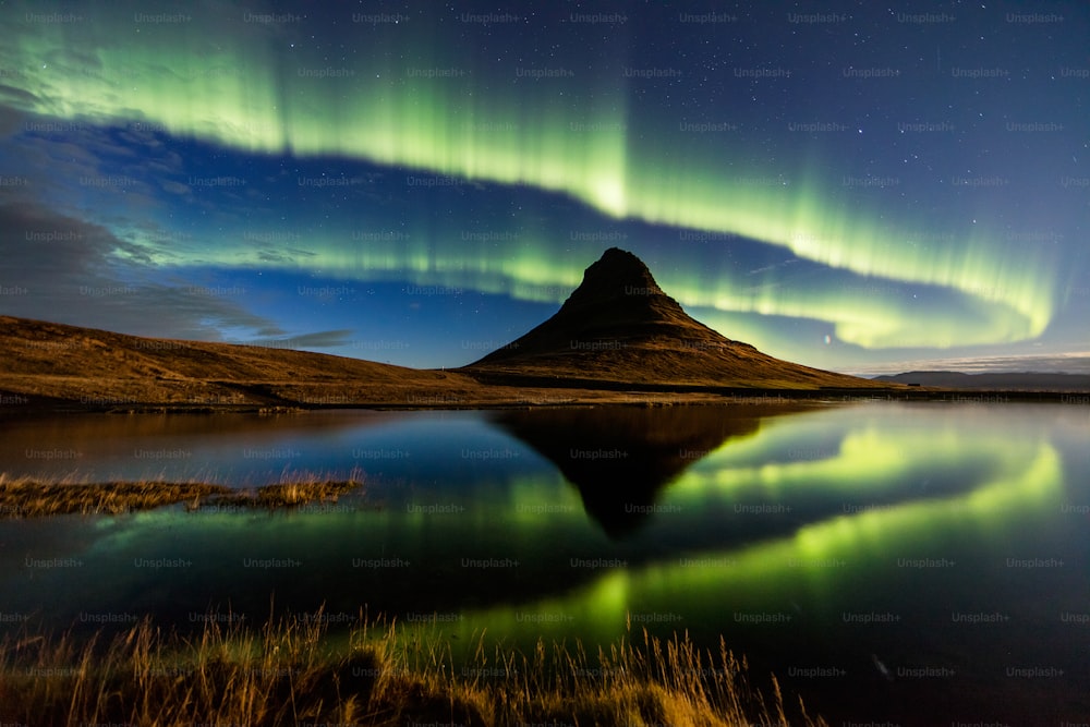 the aurora bore is reflected in the still water of a lake