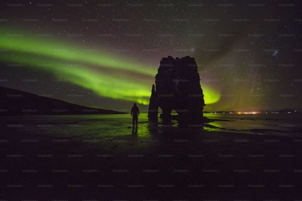 a person standing on a beach under a green and purple sky