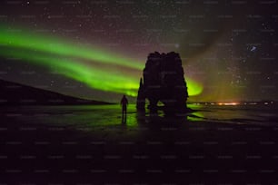 a person standing on a beach under a green and purple sky