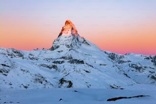 Una montagna innevata con un cielo rosa sullo sfondo