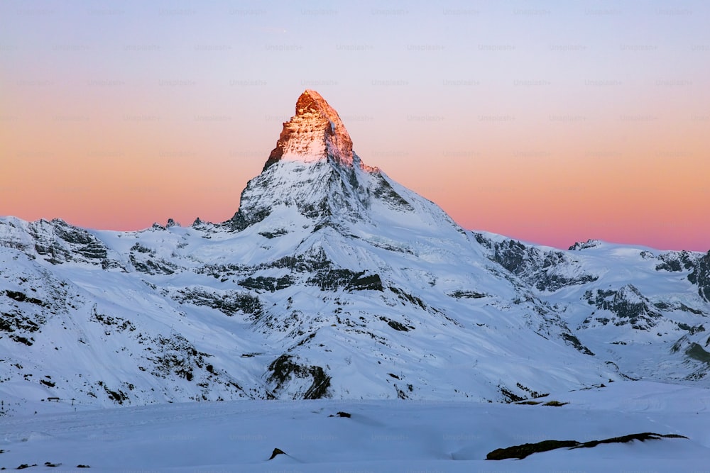 a snow covered mountain with a pink sky in the background