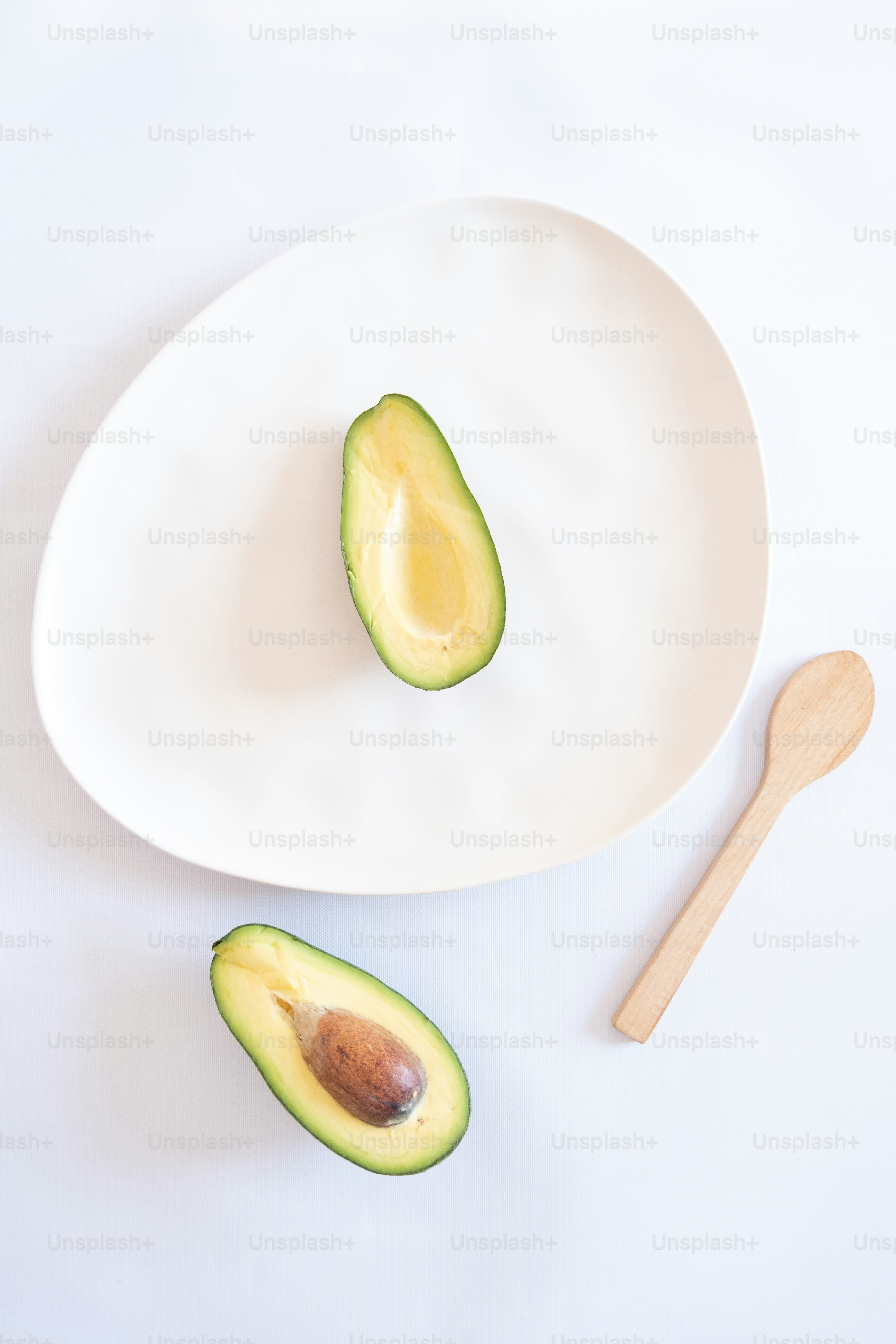 an avocado cut in half on a white plate