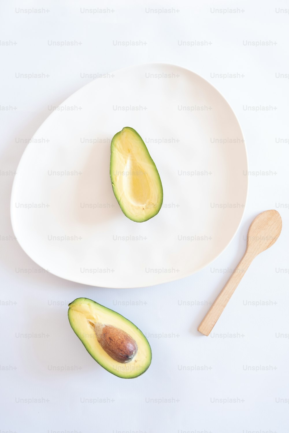 an avocado cut in half on a white plate