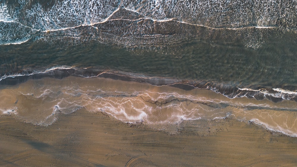 Luftaufnahme eines Strandes mit Wellen und Sand