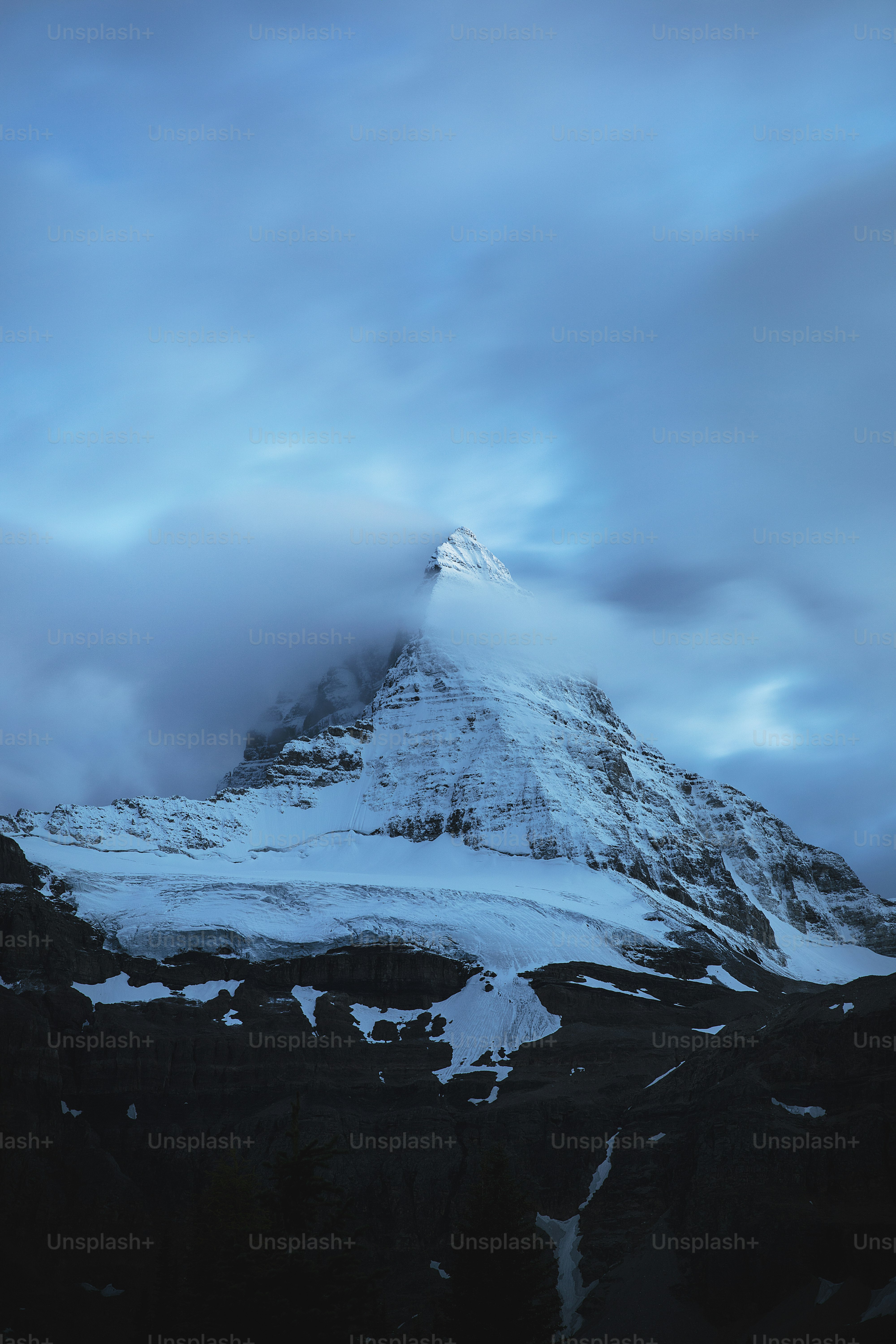 a mountain covered in snow under a cloudy sky
