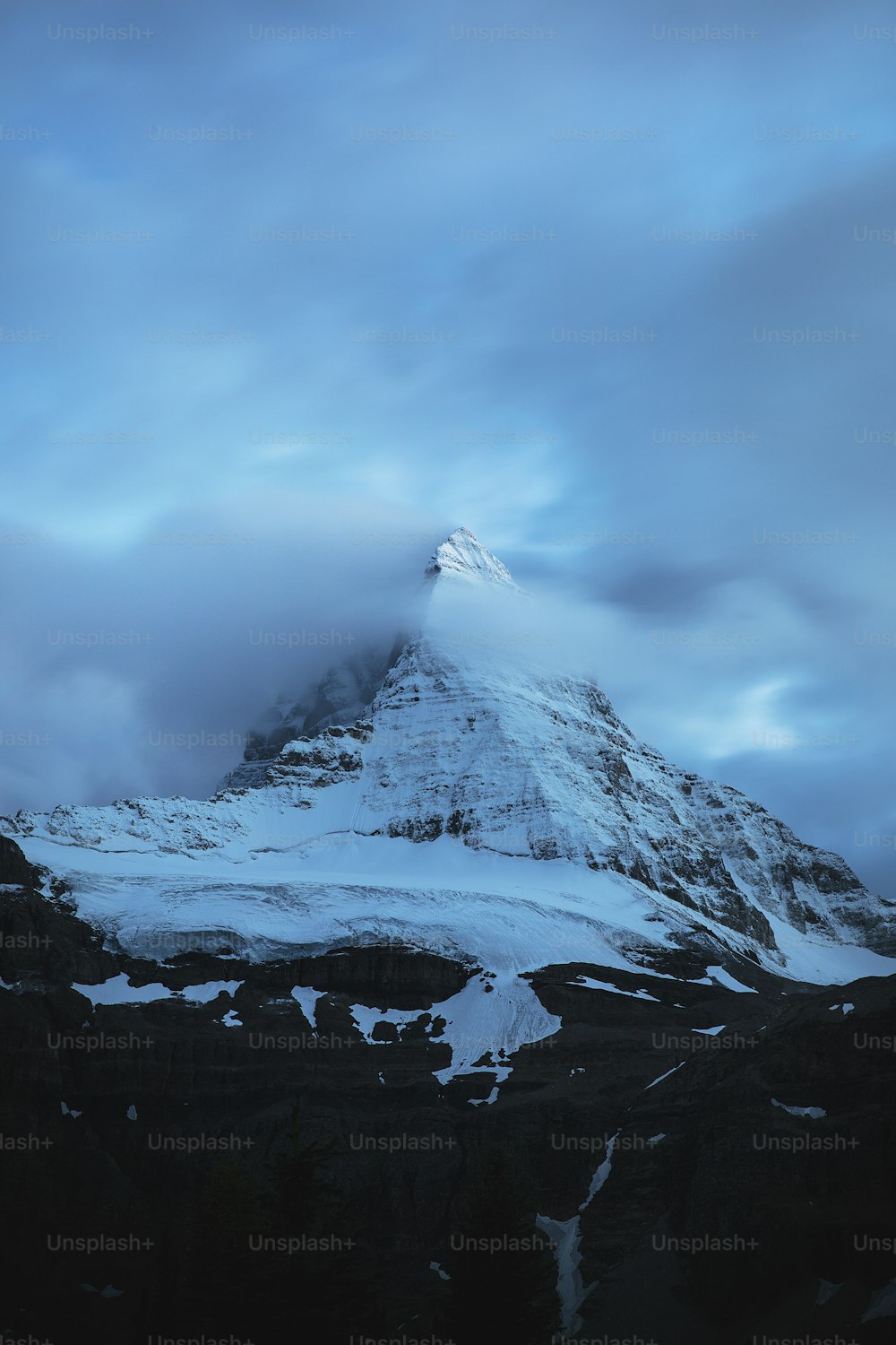 a mountain covered in snow under a cloudy sky