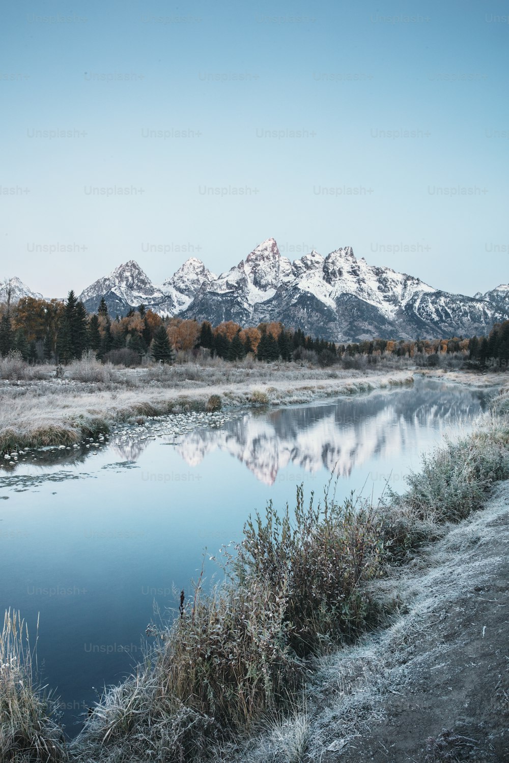 a body of water surrounded by snow covered mountains