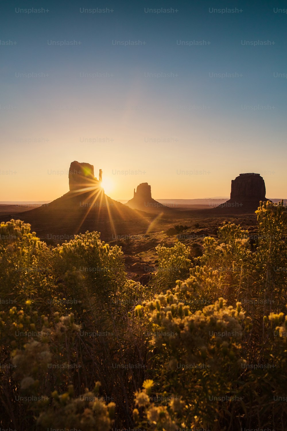 the sun is setting over a desert landscape